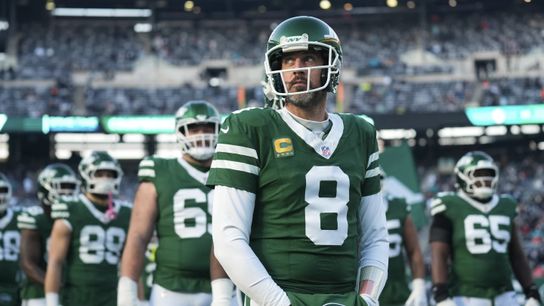 Former New York Jets quarterback Aaron Rodgers stands with teammates before a game in 2023. Former New York Jets quarterback Aaron Rodgers stands with teammates before a game in 2023.
